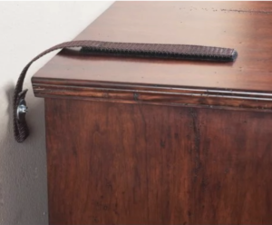 An anti-tip strap attaches a wooden dresser to the wall.